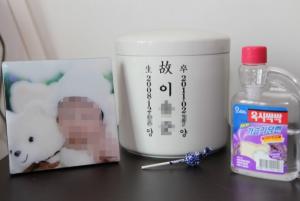 가습기 살균제로 인해 세상을 떠난 아이의 사진. 유골함 옆에는 사용했던 가습기 살균제가 놓여 있다. ⓒ환경보건시민센터